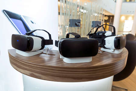 Virtual reality (VR) headsets (glasses) on a table. VR is immersive multimedia or computer-simulated reality - a computer technology that replicates an environment and simulates a user's physical presence and environment to allow for user interactionの写真素材