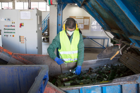 Sofia, Bulgaria - May 26, 2016: Glass waste worker is recycling glass bottles in a recycling facility. Different glass packaging bottle waste. Glass waste management.のeditorial素材