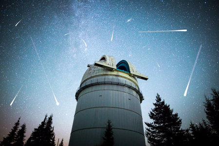 Rozhen astronomical observatory under the night sky stars. Blue sky with hundreds of stars of the Milky way. Observatory in a pine trees forest in the mountain. Vignetting. Meteor shower. Falling stars.のeditorial素材