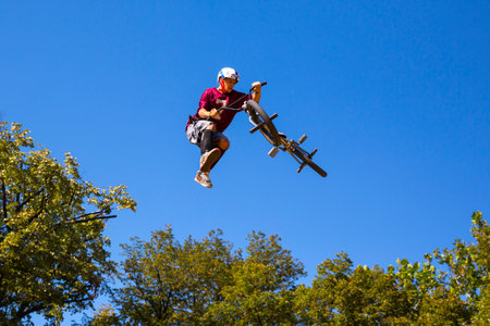 Sofia, Bulgaria - September 24, 2016: An extreme rider is making a free style jump from a ramp. The young boy with his bicycle is seen up in the air near trees.のeditorial素材