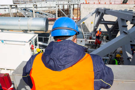 A worker in working uniform and helmet is monitoring the work on a big modern industrial subway drilling machine.の写真素材