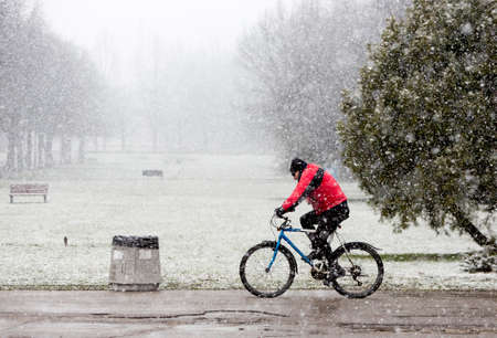 A man is biking in the park while snowing in Sofia, Bulgaria.の写真素材