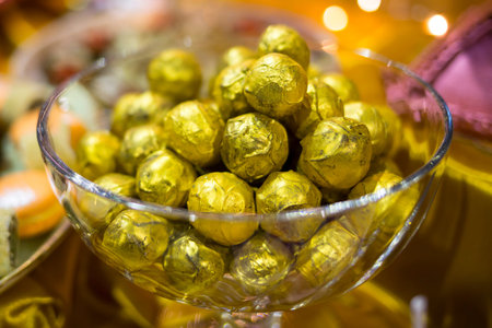 Chocolate bonbons wrapped in golden foil in a glass bowl. Extremely tasty and delicious desserts....