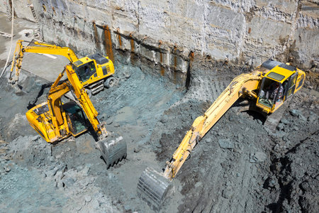 Excavators dig at a construction site of a street and a subway. Baggers transport dirt to a higher...