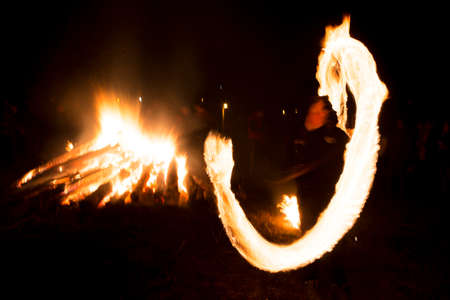 A boy spins rings of fire near a bonfire during a fire ritual celebration of Sirni Zagovezni held seven weeks before Easter. People believe they chase away evil spirits with fire rituals. Village of Lozen, Bulgaria.の写真素材