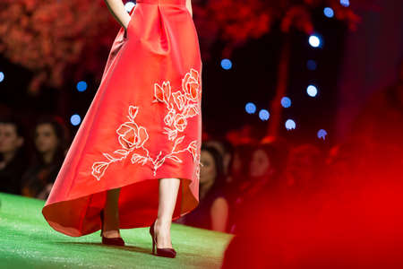A female model walks the runway in a beautiful red dress during a Fashion Show. Fashion catwalk event showing new collection of clothes.の写真素材