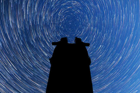 A view of the stars of the Milky Way. Comet mode. Meteor Shower. Falling stars. Perseid Meteor Shower in 2017. Timelapse. Astronomical observatory silhouette in the middle.の写真素材