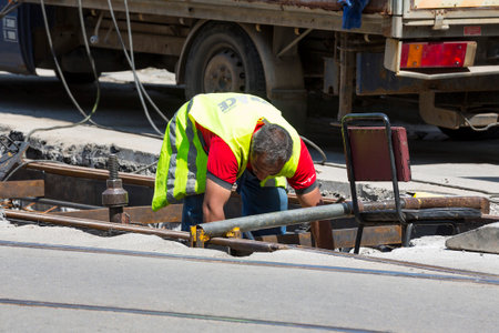 Sofia, Bulgaria - 12 July 2017: Road construction worker repairs tram car's railroad lines on a construction site.のeditorial素材
