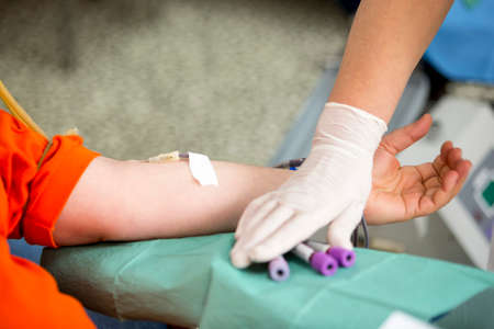 The hand of a woman who donates blood. Female donor gives blood in a mobile blood donation center. Blood samples. Hand of the nurse with protective gloves.の写真素材