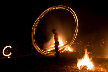 A boy spins rings of fire near a bonfire during a fire ritual celebration of Sirni Zagovezni held seven weeks before Easter. People believe they chase away evil spirits with fire rituals. Village of Lozen, Bulgaria.の写真素材