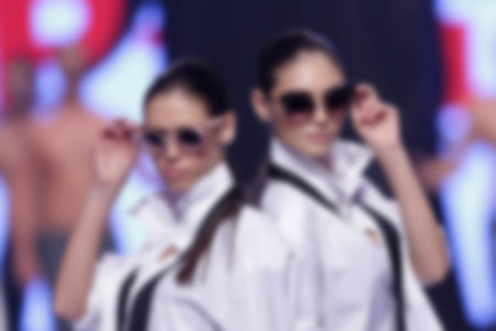 Blurry out of focus (defocus) female modes snow sunglasses in white shirts during a fashion show week.の写真素材