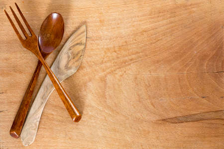 Wooden knife, spoon and fork on a wooden background.の写真素材