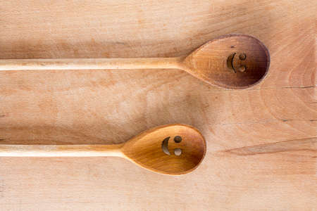 Wooden smiley face spoon on a wooden background. Studio shot. Set of kitchen utensil.の写真素材