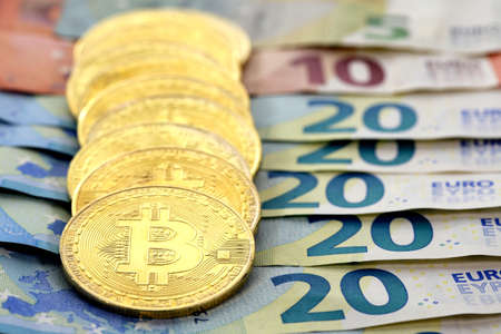 Virtual cryptocurrency money Bitcoin golden coins on European Union EU Euro 5, 10 and 20 banknotesの写真素材