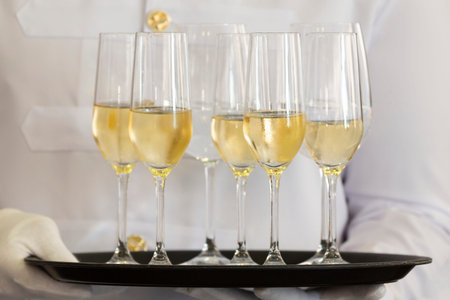 Waiter holds a tray of white wine, champagne and water.