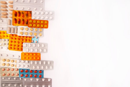 Different colorful pills and capsules in plastic packs - blisters stacked. Global pharmaceutical...