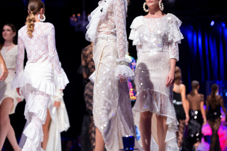 Female models walk the runway in different white dresses during a Fashion Show. Fashion catwalk event showing new collection of clothes.のeditorial素材