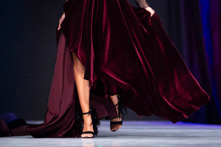 Female model walks the runway in red dress during a Fashion Show. Legs and shoes only. Fashion catwalk event showing new collection of clothes. Single female model in beautiful dress.のeditorial素材