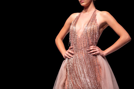 Female model walks the runway in pink dress isolated on a black background during a Fashion Show. Fashion catwalk event showing new collection of clothes. Single female model in beautiful dress.のeditorial素材