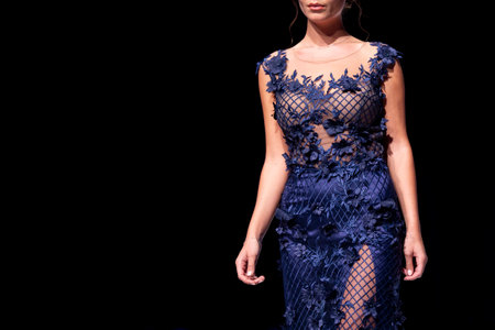 Female model walks the runway in blue dress isolated on a black background during a Fashion Show. Fashion catwalk event showing new collection of clothes. Single female model in beautiful dress.のeditorial素材