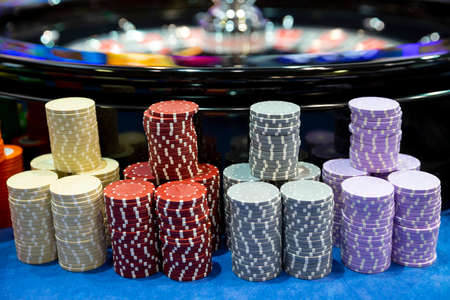 Colourful roulette chips in a casino on a gambling table near roulette wheel. Lots of chips with different nomination and colours.の写真素材