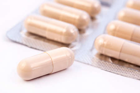 Beige capsules in silver plastic pack - blister. Global pharmaceutical industry for billions dollars per year. Pharmaceutical drugs for use as medications. Studio shot. Isolated on a white background.の写真素材