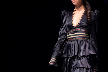 Female model walks the runway in black dress isolated on a black background during a Fashion Show. Fashion catwalk event showing new collection of clothes. Single female model in beautiful dress.のeditorial素材
