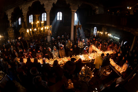 Blagoevgrad, Bulgaria - February 10, 2019: Worshippers light candles on jars with honey during a religious ritual marking the day of Saint Haralampi - the Orthodox patron saint of beekeepers - in the church of the Presentation of the Blessed Virgin.のeditorial素材