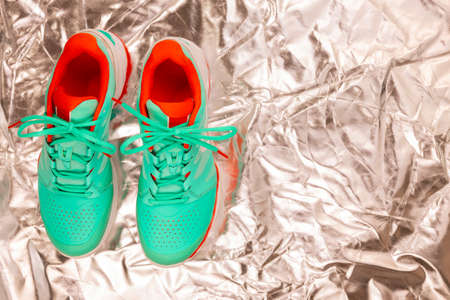 Red, cyan, white pair of new tennis shoes in studio shot over reflective white background. Directly from above.の写真素材