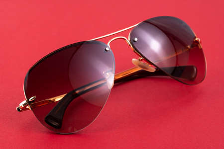 Studio shot of brown aviator sunglasses on red background.の写真素材