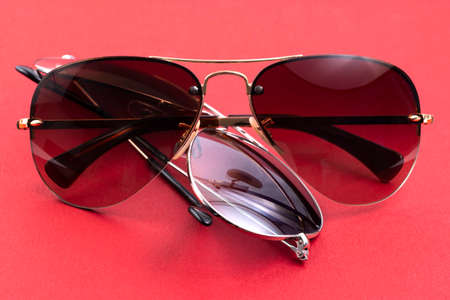 Studio shot of brown and blue aviator sunglasses on red background.の写真素材
