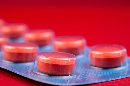 Red pills in blue plastic pack - blister. Global pharmaceutical industry for billions dollars per year. Pharmaceutical drugs for use as medications. Studio shot. Isolated on a red background.の写真素材