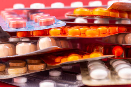 Different colorful capsules and pills in plastic packs - blisters stacked. Global pharmaceutical industry for billions dollars per year. Pharmaceutical drugs for use as medications. Studio shot.の写真素材