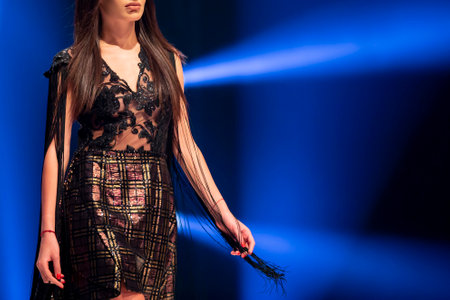 Female model walks the runway in a beautiful black dress during a Fashion Show. Fashion catwalk event showing new collection of clothes. Blue background. Unrecognizable person.のeditorial素材