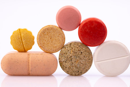 Colorful pills isolated on white reflective background. Global pharmaceutical industry for billions...