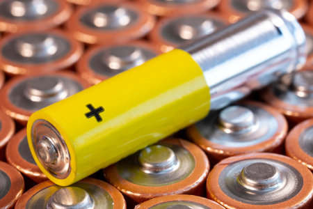 Multiple used AA alkaline batteries and a single AAA battery are seen arranged in a pile. Closeup...