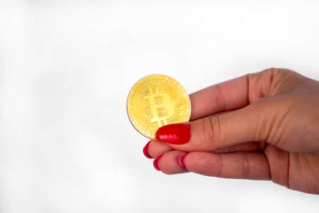 Virtual cryptocurrency money Bitcoin golden coin in the right hand of a woman with red nail polish. The future of money. Isolated on a white background.の写真素材