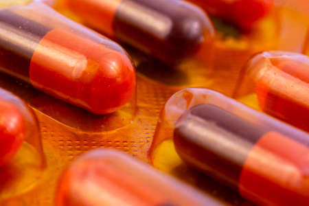Red capsules in orange plastic pack - blister. Global pharmaceutical industry for billions dollars per year. Pharmaceutical drugs for use as medications. Studio shot.の写真素材
