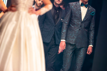 Male models walk the runway in elegant suits during a Fashion Show. Fashion catwalk event showing new collection of clothes. Unrecognizable people.のeditorial素材