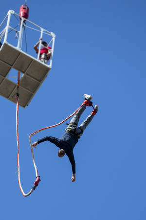 A man jumps with a bungee from a crane top against the blue sky. Unrecognizable person.の写真素材