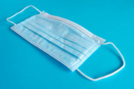 Blue surgical protective mask on a blue background. Coronavirus (COVID-19) hysteria is leading to mass mask shortages in the beginning of 2020.の写真素材