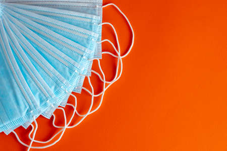 Blue surgical protective mask on an orange background. Coronavirus (COVID-19) hysteria is leading to mass mask shortages in the beginning of 2020.の写真素材