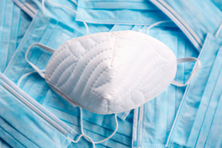 White protective mask on blue surgical masks. Coronavirus (COVID-19) hysteria is leading to mass...