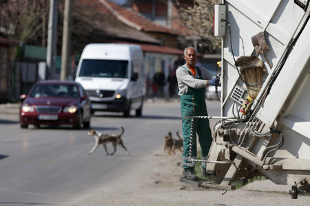 Sofia, Bulgaria - 11 April, 2020: Garbage truck worker travels on the vehicle during his work shift,のeditorial素材