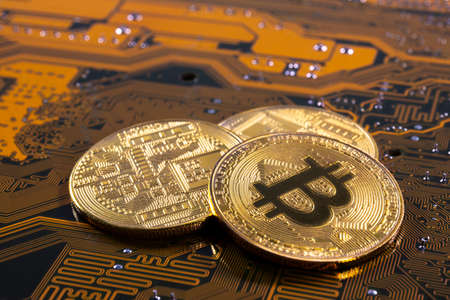 Virtual cryptocurrency money Bitcoin golden coins on a computer printed circuit board PCB. The future of money. Computational equipment. Yellow and green mother board.の写真素材