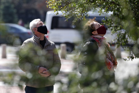 Sofia, Bulgaria - 30 March, 2020: A woman and a man wearing multiple use protective face masks during the Coronavirus disease COVID-19 outbreak epidemic walk in a park in Sofia.のeditorial素材
