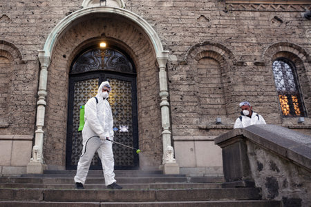 Sofia, Bulgaria - 11 April, 2020: Worker sprays disinfectant outside of Sveta Nedelya Church against the spread of coronavirus disease COVID-19.のeditorial素材