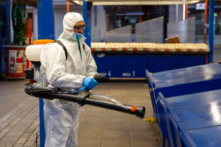 Sofia, Bulgaria - 7 April, 2020: Worker sprays disinfectant outside of ? food market against the spread of coronavirus disease COVID-19.のeditorial素材