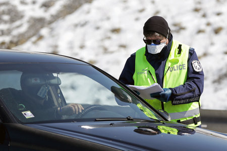 Sofia, Bulgaria - 3 April, 2020: A police officer checks a car drriver at one of the exits of Sofia, following restrictions on non-essential travel between cities and towns due to coronavirus disease.のeditorial素材