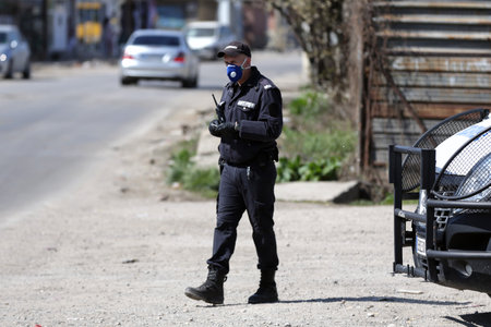 Sofia, Bulgaria - 11 April, 2020: A police officer in a gendarmery uniform with protective face mask against the spread of coronavirus disease COVID-19 stands on his post near a checkpoint.のeditorial素材